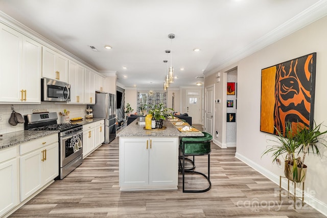 kitchen with ornamental molding, appliances with stainless steel finishes, a kitchen bar, and decorative backsplash