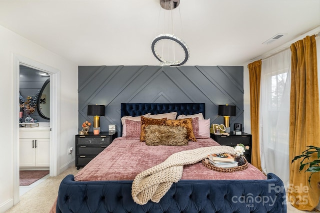bedroom with connected bathroom, wooden walls, carpet floors, visible vents, and baseboards