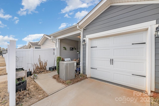 garage featuring driveway, fence, and central AC