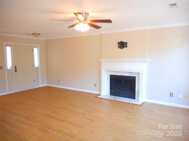 unfurnished living room with visible vents, wood finished floors, ornamental molding, and a fireplace