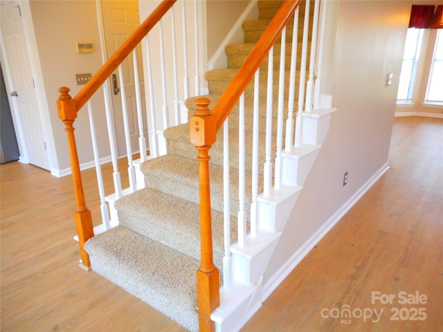 stairs featuring wood finished floors and baseboards