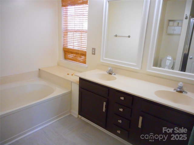 bathroom with double vanity, a garden tub, and a sink