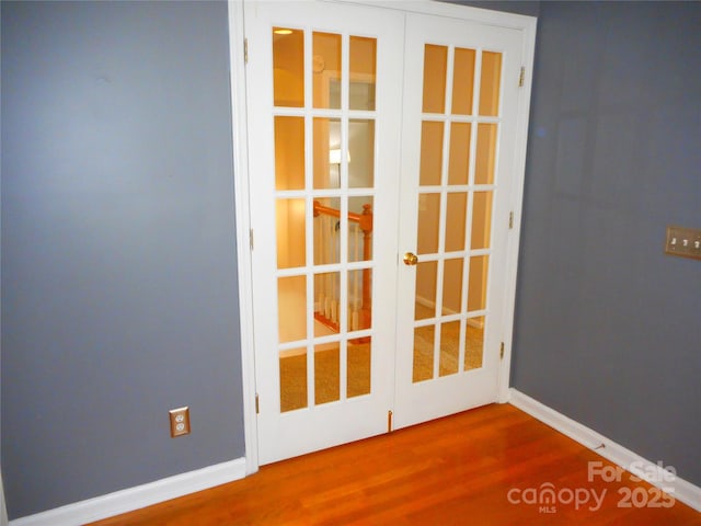 interior space featuring wood finished floors, french doors, and baseboards