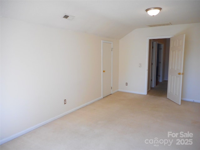 unfurnished room with lofted ceiling, baseboards, visible vents, and light carpet