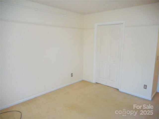 spare room with baseboards and light carpet