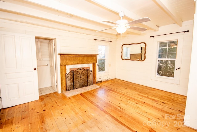 unfurnished living room featuring hardwood / wood-style floors, a ceiling fan, beam ceiling, and a tile fireplace