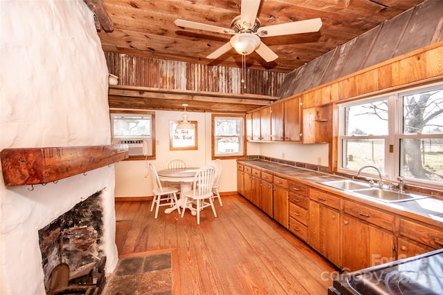 kitchen featuring tile countertops, a sink, light wood-style flooring, and a healthy amount of sunlight