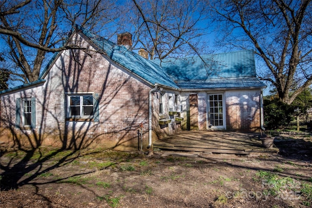 view of side of property featuring a wooden deck, a chimney, and brick siding