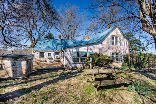 back of property featuring brick siding, a chimney, a storage shed, and an outdoor structure