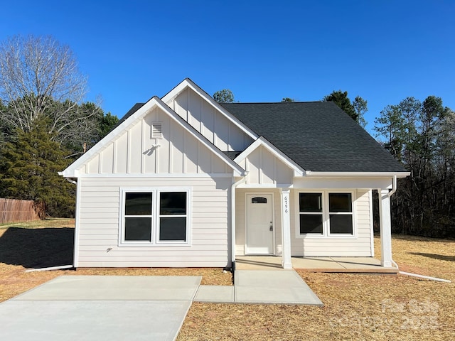 modern farmhouse with a patio, fence, board and batten siding, and a shingled roof