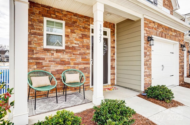 view of exterior entry featuring driveway, a porch, and brick siding