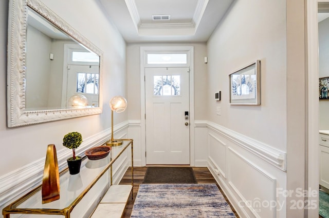 foyer with ornamental molding, wainscoting, and a healthy amount of sunlight