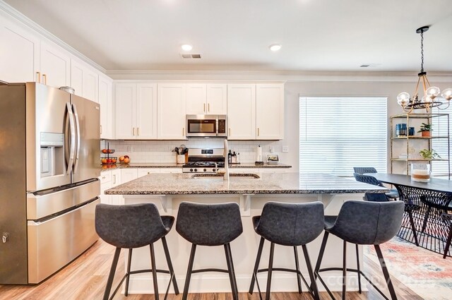 kitchen with light wood finished floors, white cabinetry, stainless steel appliances, and a sink