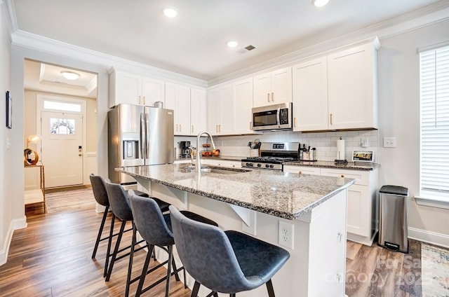 kitchen featuring tasteful backsplash, visible vents, appliances with stainless steel finishes, a breakfast bar, and a sink