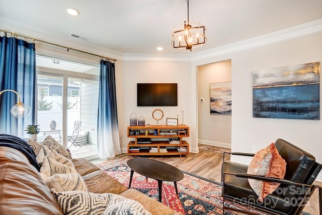 living room with a notable chandelier, wood finished floors, visible vents, baseboards, and crown molding