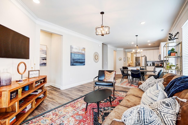 living area with light wood finished floors, baseboards, ornamental molding, an inviting chandelier, and recessed lighting