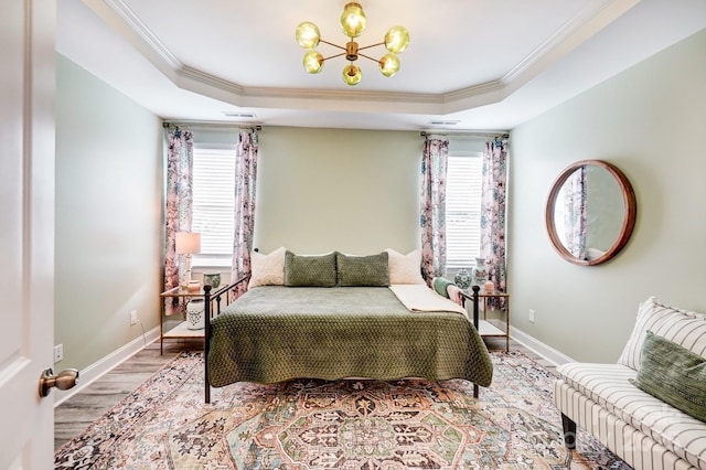 bedroom featuring multiple windows, a chandelier, and a raised ceiling