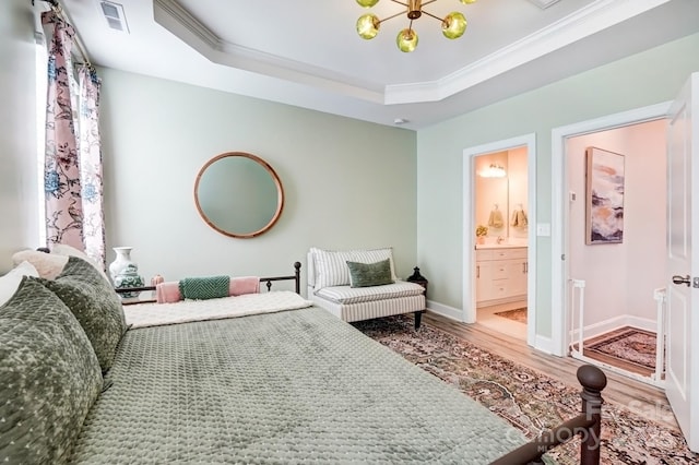 bedroom featuring visible vents, ornamental molding, wood finished floors, a tray ceiling, and a notable chandelier