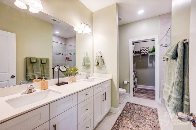 full bath featuring a sink, a shower stall, toilet, and double vanity