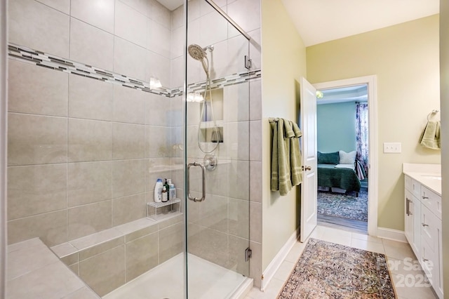 ensuite bathroom featuring tile patterned flooring, connected bathroom, vanity, baseboards, and a stall shower