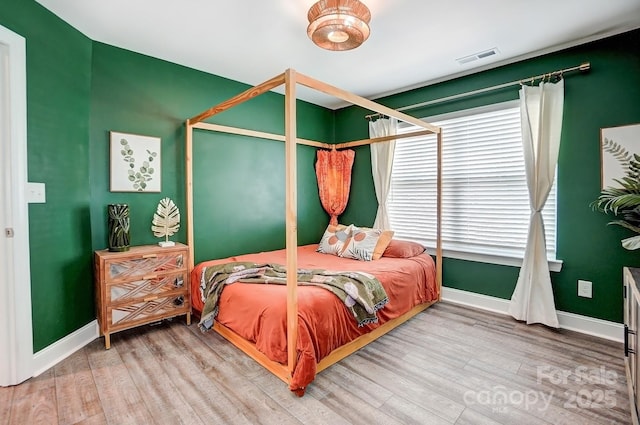 bedroom featuring visible vents, baseboards, and wood finished floors