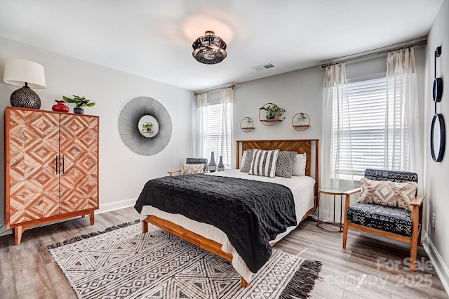 bedroom featuring wood finished floors, visible vents, and baseboards