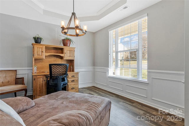 bedroom featuring visible vents, wainscoting, a tray ceiling, wood-type flooring, and an inviting chandelier