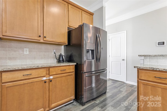 kitchen with stainless steel fridge, wood finished floors, light stone countertops, crown molding, and backsplash