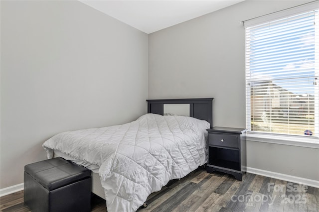 bedroom with multiple windows, baseboards, and wood finished floors