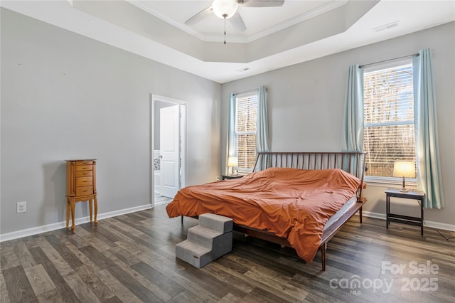 bedroom with crown molding, a raised ceiling, visible vents, wood finished floors, and baseboards