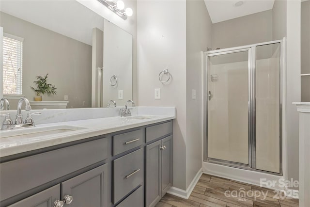 full bath featuring a sink, a shower stall, and wood finished floors