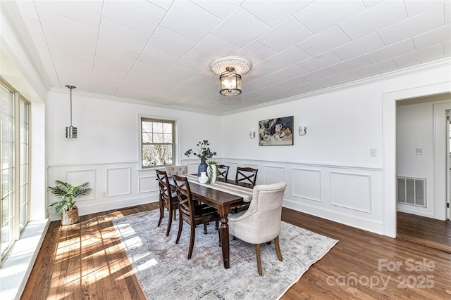 dining room with visible vents, ornamental molding, and wood finished floors