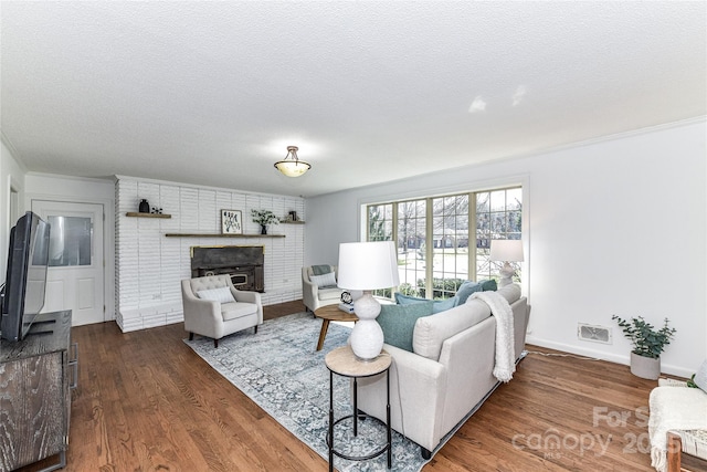 living room featuring visible vents, baseboards, a fireplace, dark wood-style flooring, and a textured ceiling