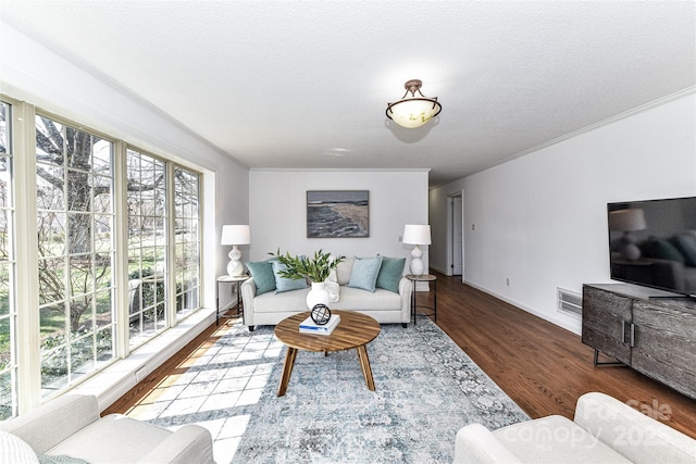 living area with baseboards, wood finished floors, visible vents, and a textured ceiling