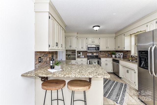 kitchen with a sink, tasteful backsplash, appliances with stainless steel finishes, and a peninsula