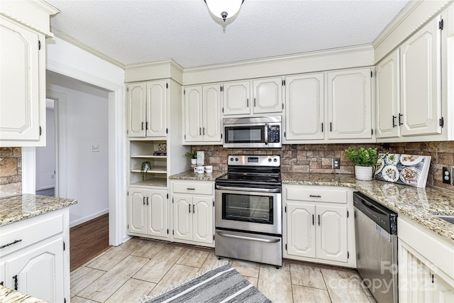 kitchen featuring backsplash, white cabinetry, stainless steel appliances, and light stone countertops