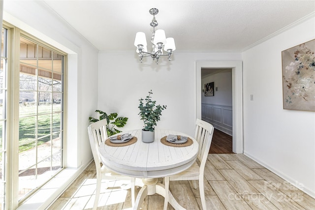 dining area featuring light wood-style floors, a chandelier, crown molding, and a textured ceiling