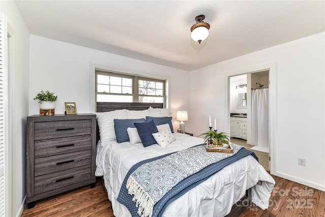 bedroom featuring ensuite bath, wood finished floors, baseboards, and a textured ceiling