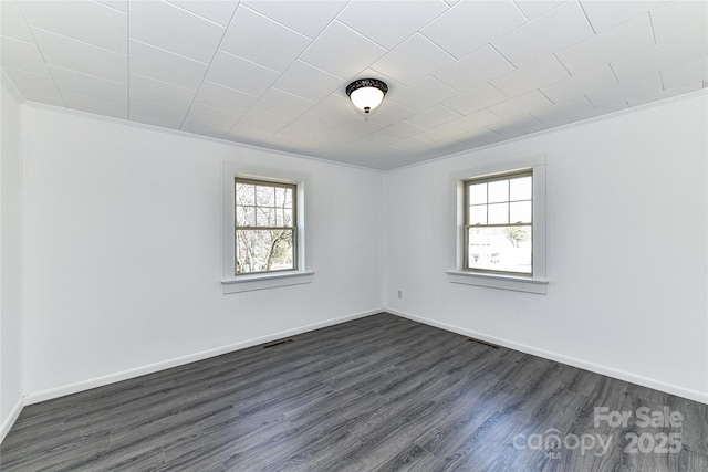 empty room with visible vents, baseboards, dark wood-type flooring, and crown molding