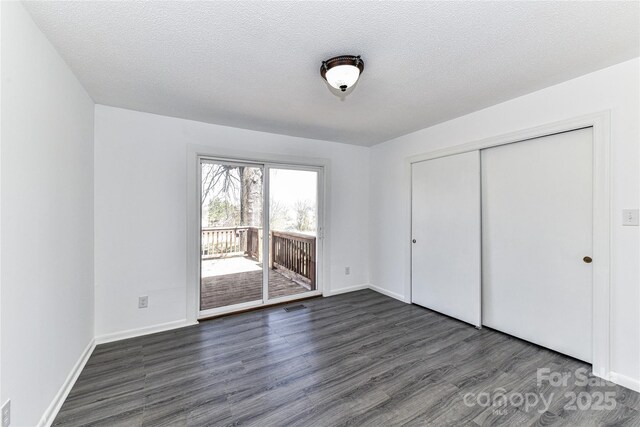 unfurnished bedroom featuring access to exterior, baseboards, dark wood finished floors, a closet, and a textured ceiling