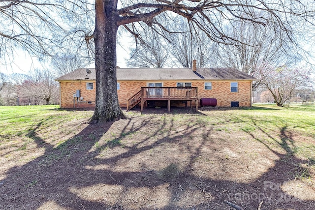 rear view of property featuring brick siding, a wooden deck, a chimney, and heating fuel