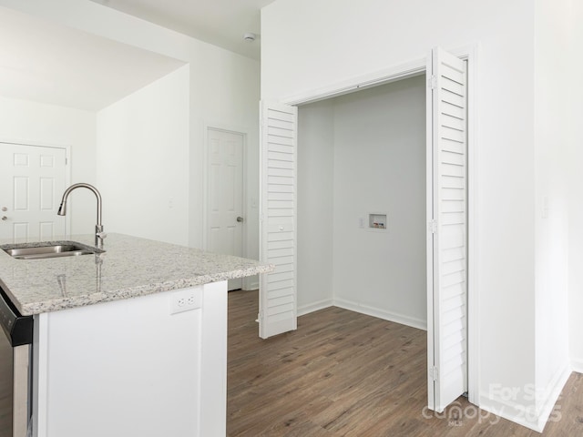 kitchen featuring light stone countertops, a sink, dishwasher, and wood finished floors