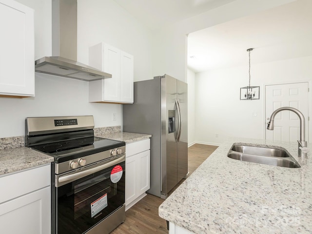 kitchen with wood finished floors, a sink, white cabinets, appliances with stainless steel finishes, and wall chimney exhaust hood