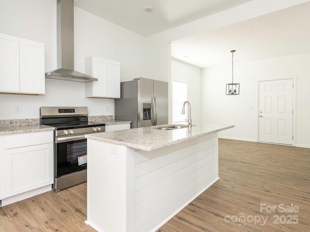 kitchen with light wood finished floors, wall chimney exhaust hood, appliances with stainless steel finishes, and a sink