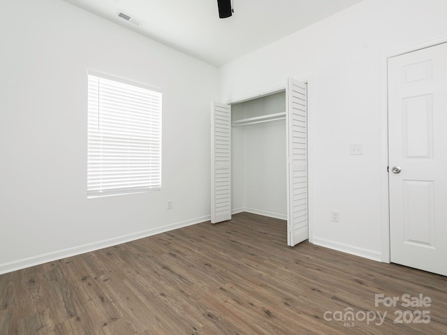 unfurnished bedroom featuring visible vents, a closet, baseboards, and wood finished floors