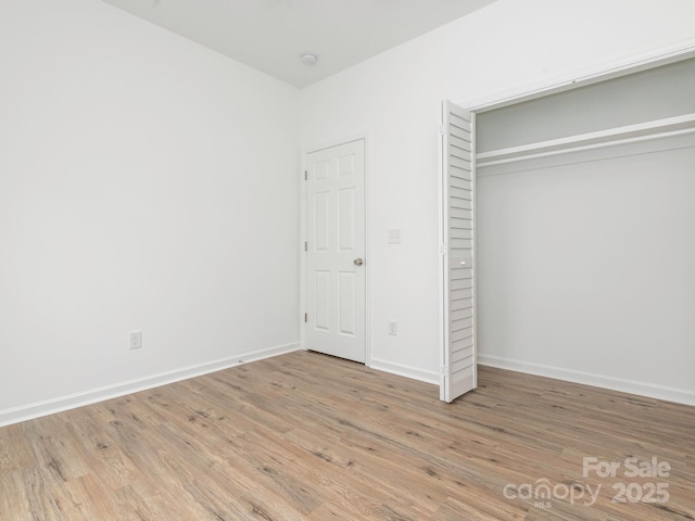 unfurnished bedroom with a closet, wood finished floors, and baseboards