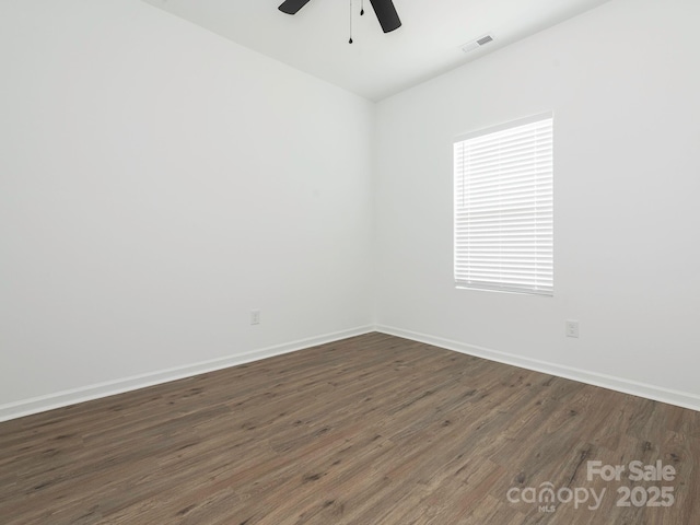 unfurnished room with ceiling fan, baseboards, visible vents, and dark wood finished floors