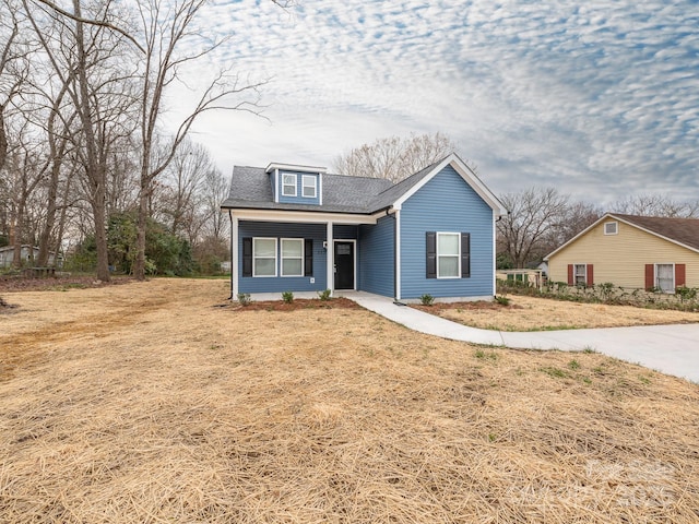 view of front of property with a shingled roof and a front lawn