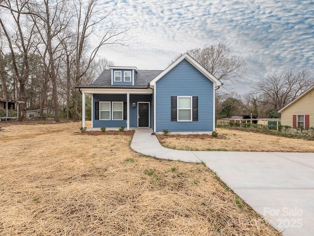 bungalow-style home featuring a front lawn and roof with shingles