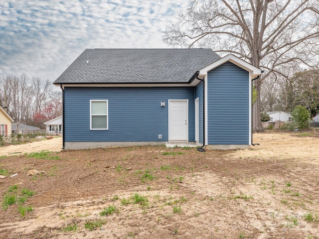 rear view of property featuring roof with shingles